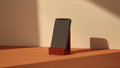 Soporte de teléfono RUMI impreso en 3D con textura estriada terracota sosteniendo un smartphone
