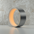 Modern silver cylindrical light with warm glow on a marble surface
